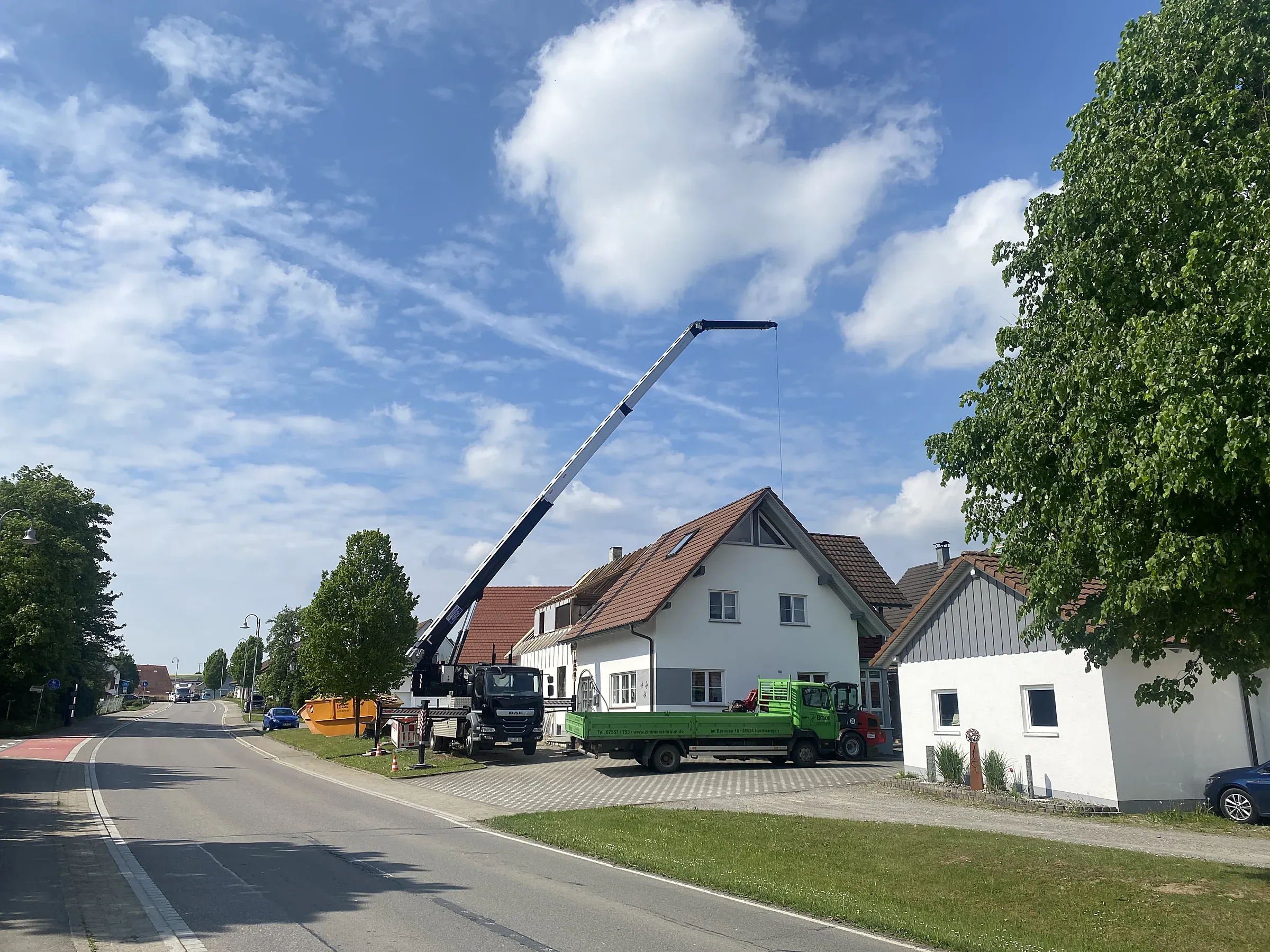 Aufgestellter Autokran mit ausgefahrenem Ausleger vor einem Wohnhaus