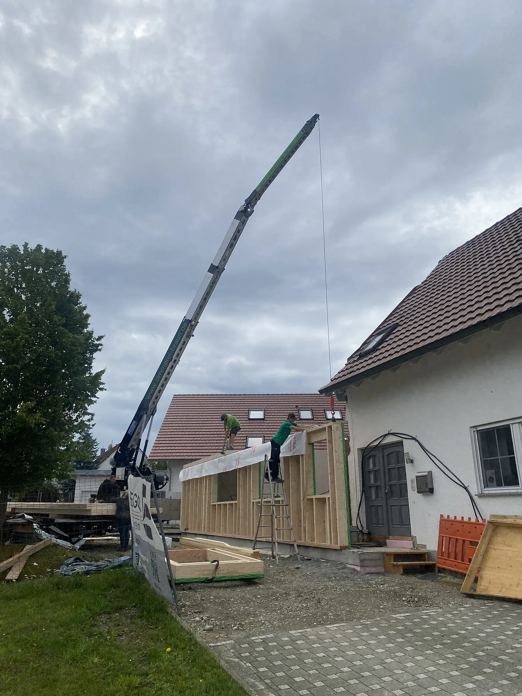 Autokran der Zimmerei Braun hebt ein Holzwandelement auf einer Baustelle